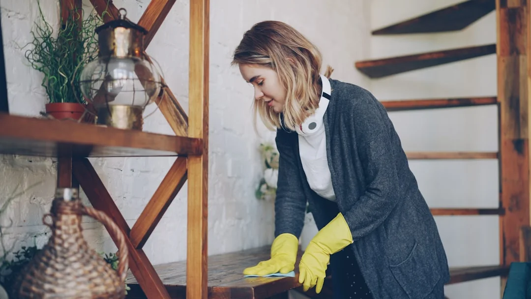 A couple wrapping furniture in a bright apartment, preparing to move.